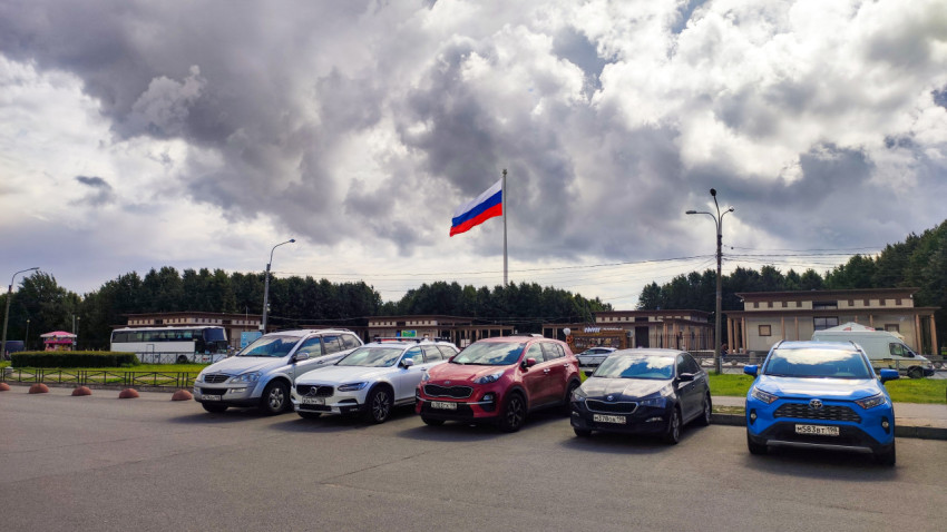 Парковка автомобилей и российский флаг на фоне облачного неба