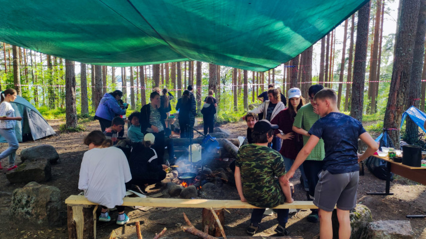 Группа людей у костра в лесном лагере