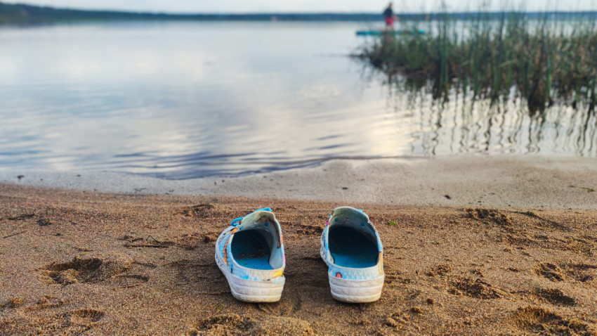 Пляжные тапочки на песчаном берегу у воды
