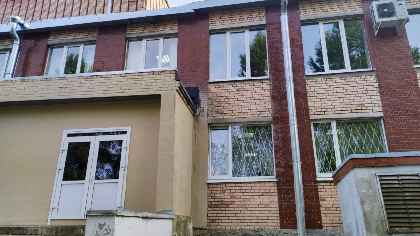 Фасад кирпичного здания с металлической трубой и решётками на окнах