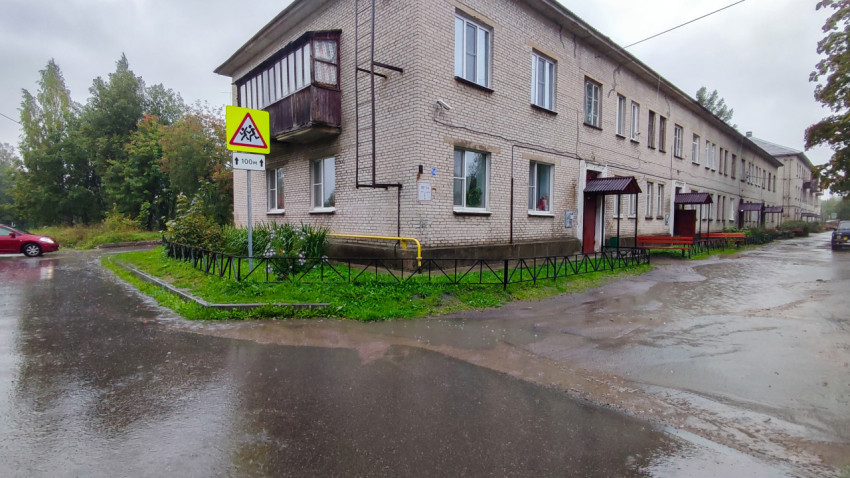 Угловой фасад жилого дома советской постройки в дождь