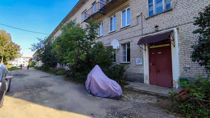 Подъезд жилого дома и укрытый мотоцикл во дворе