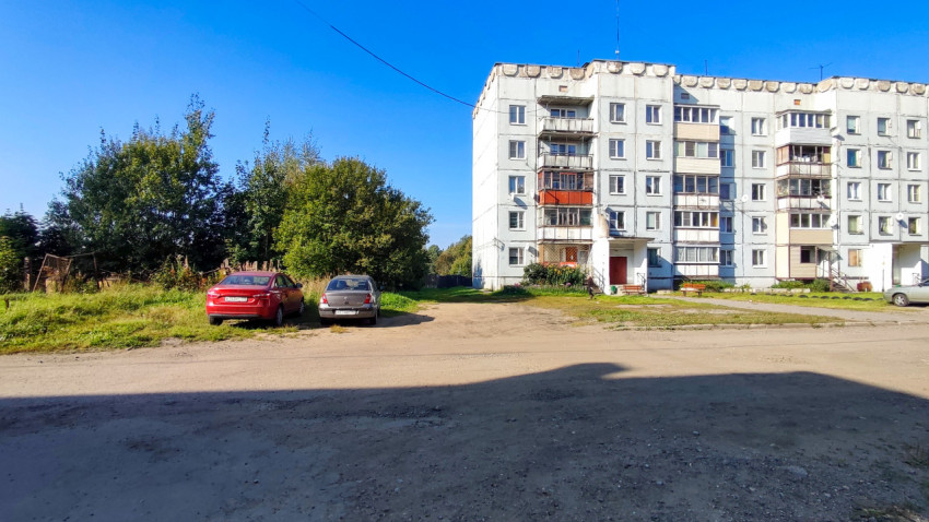 Пятиэтажный жилой дом советской постройки и открытая площадка с машинами
