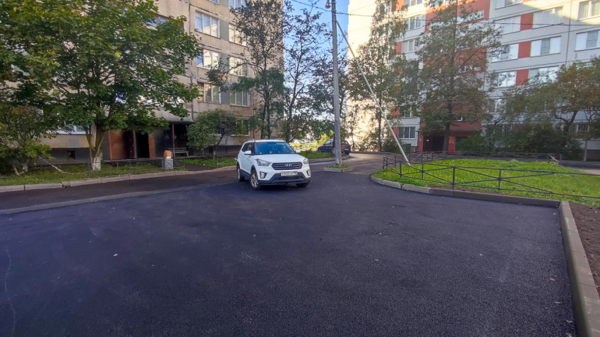 Двор жилого дома с припаркованными автомобилями после ремонта асфальта