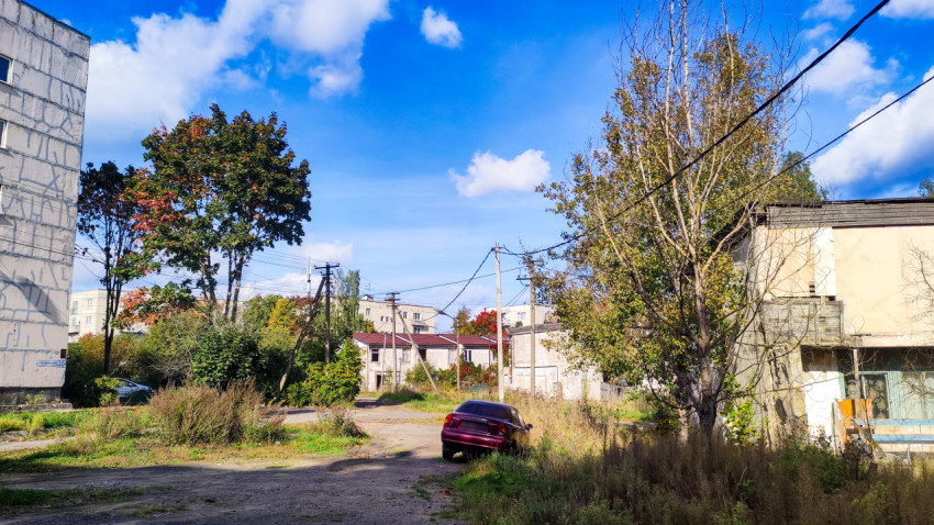 Двор старого жилого квартала с деревянными домами и электролиниями