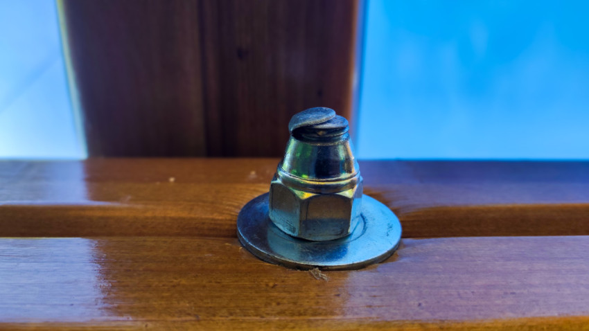 Металлический болт с шайбой на деревянной поверхности конструкции