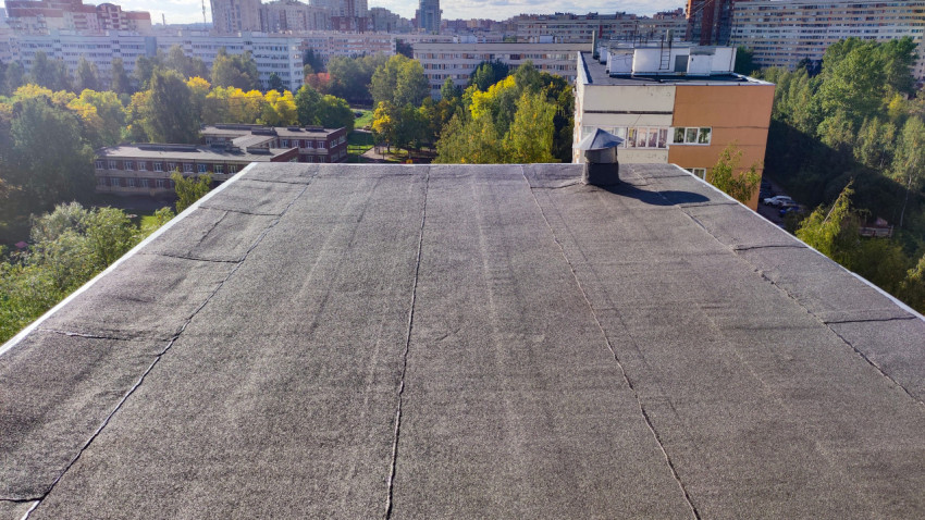 Плоская кровля жилого дома с видом на город и зелёные насаждения