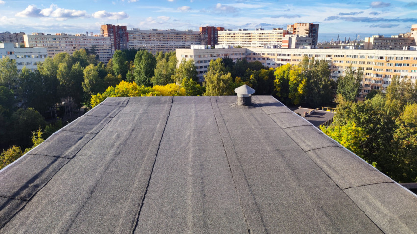 Плоская кровля жилого дома с вентиляционным выходом и видом на район