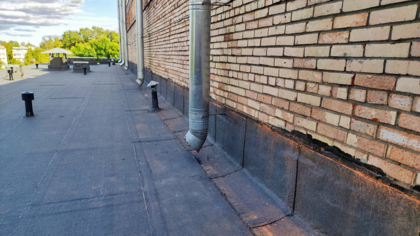 Кровля кирпичного здания с водосточными трубами и вентиляционными выходами