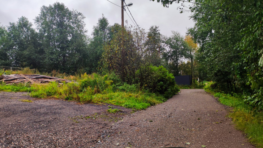 Гравийная дорога у кучи строительных досок в зелёной зоне