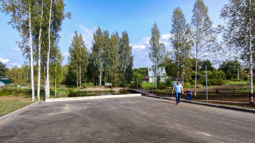 Асфальтированная площадка у пруда с пешеходным мостиком