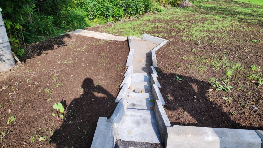 Бетонный ливневый лоток на откосе с зелёным покровом