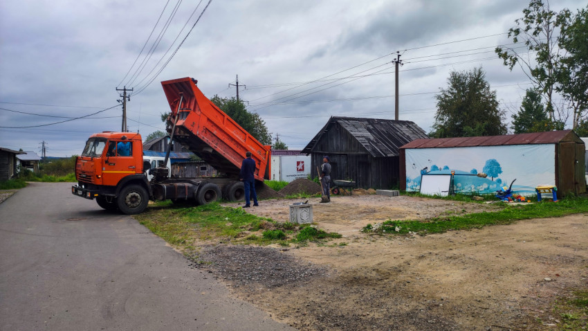 Разгрузка песка самосвалом у частных построек