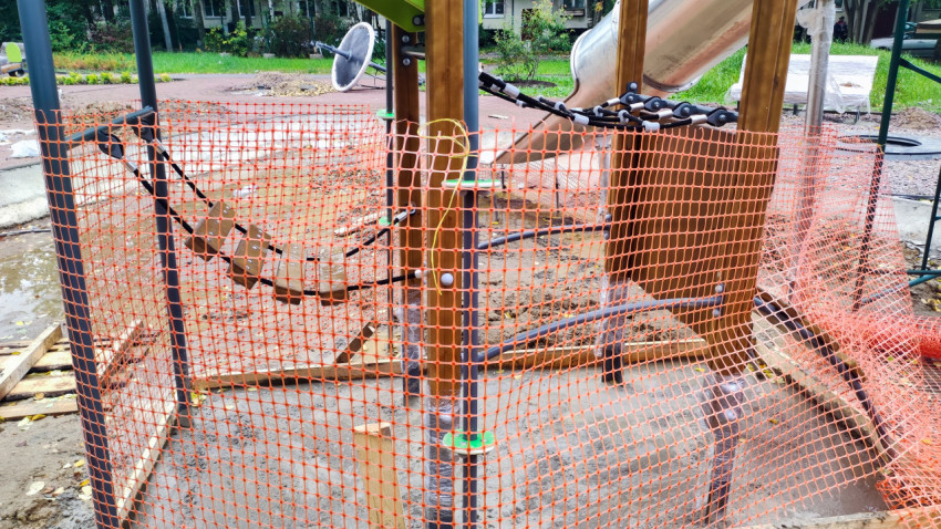 Детская площадка с ограждением из сигнальной сетки на этапе строительства