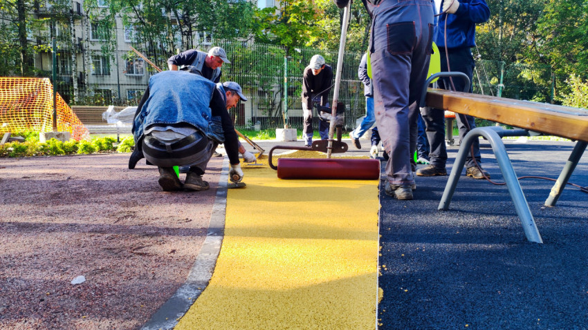 Укладка желтого покрытия на детской площадке крупным планом