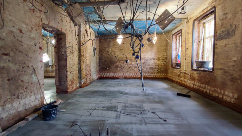 Помещение с очищенными кирпичными стенами и проводами временного освещения