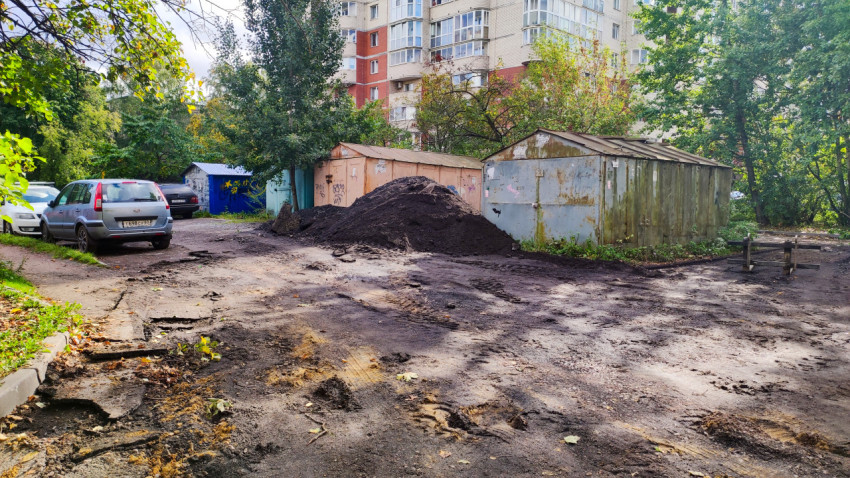 Грунтовая площадка с металлическими гаражами и кучей грунта во дворе