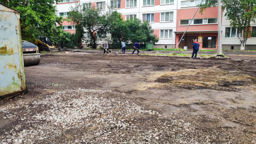 Рабочие выравнивают грунт при подготовке основания под асфальт