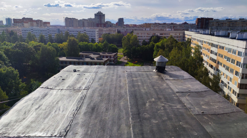 Вид на плоскую кровлю жилого дома с вентиляционной трубой