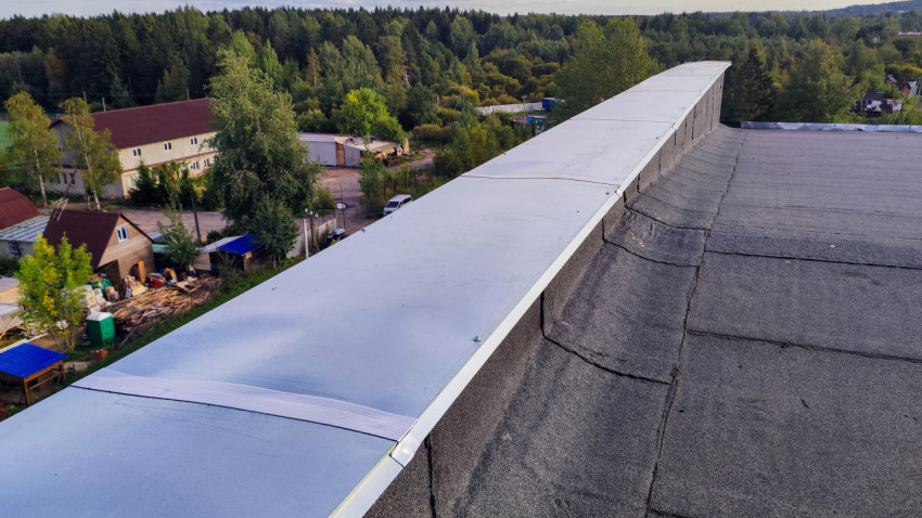 Парапет крыши с металлическим покрытием и видом на частный сектор