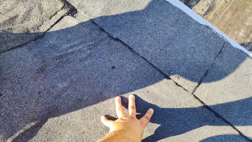 Осмотр шва рулонной кровли рукой специалиста
