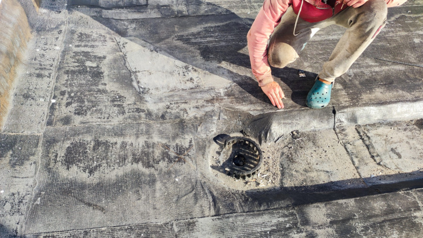 Осмотр водосточного воронки на кровле после демонтажа покрытия