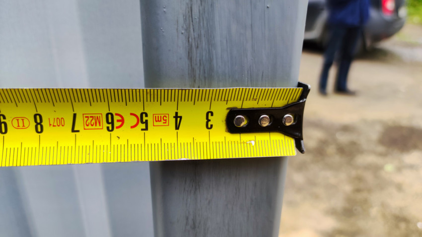 Замер толщины металлической стойки рулеткой