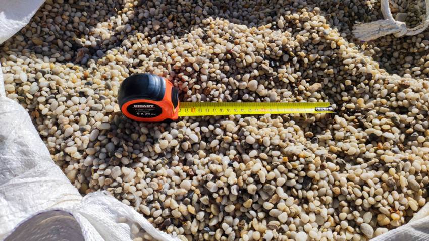 Рулетка на фоне мелкой гальки строительного материала