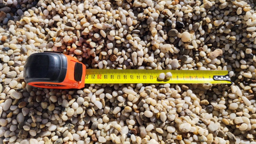 Измерительная лента на фоне мелкого гравия