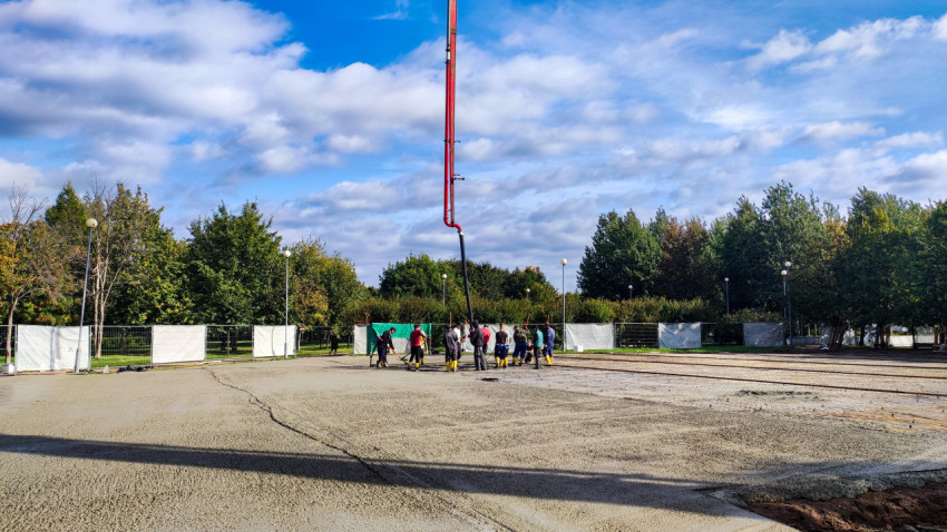 Рабочие выполняют заливку бетона на открытой строительной площадке