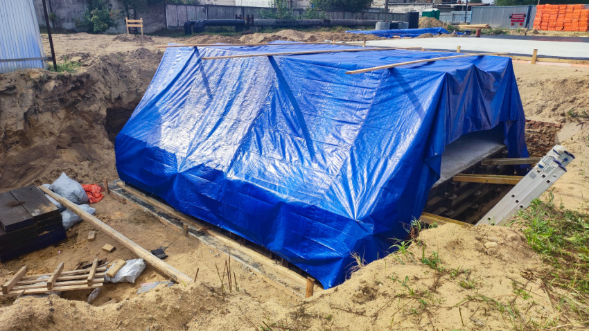 Защита бетонного сооружения под синим тентом в котловане