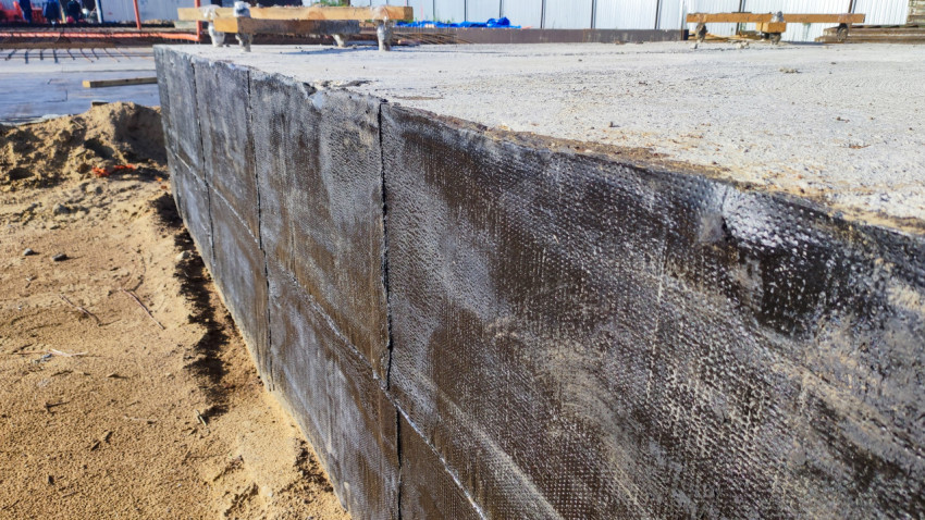 Битумная изоляция бетонных стен фундамента крупным планом