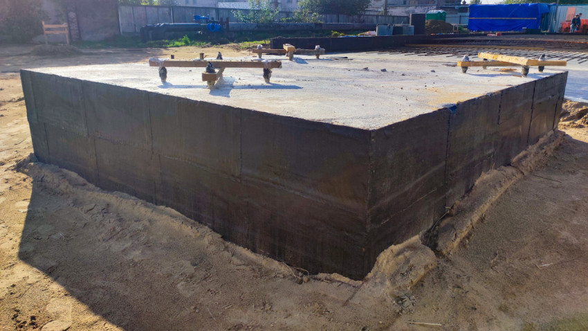 Монолитный фундамент с нанесенной битумной изоляцией на песчаном основании