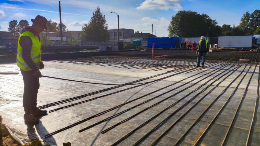 Рабочие укладывают арматуру на площадке под бетонное основание