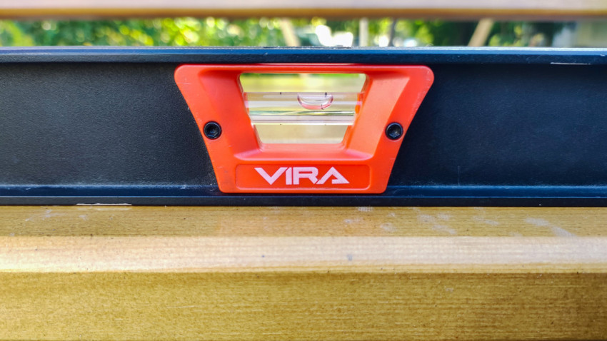 Проверка уровня поверхности деревянной детали строительным инструментом