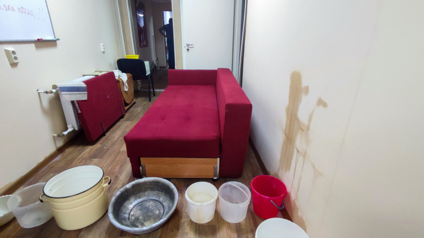 Комната с диваном и емкостями для сбора воды при протечке