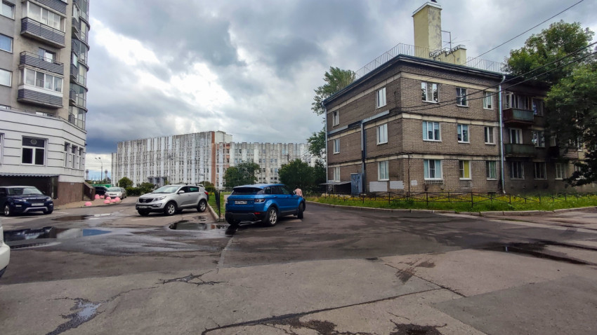 Автомобили и жилые дома во дворе с асфальтовым покрытием