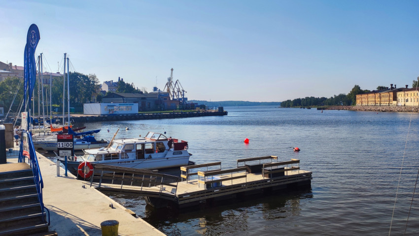 Пристань с моторными лодками и историческим зданием в Выборге