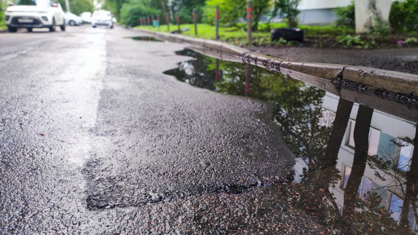 Лужа на асфальтированной дороге возле бордюра