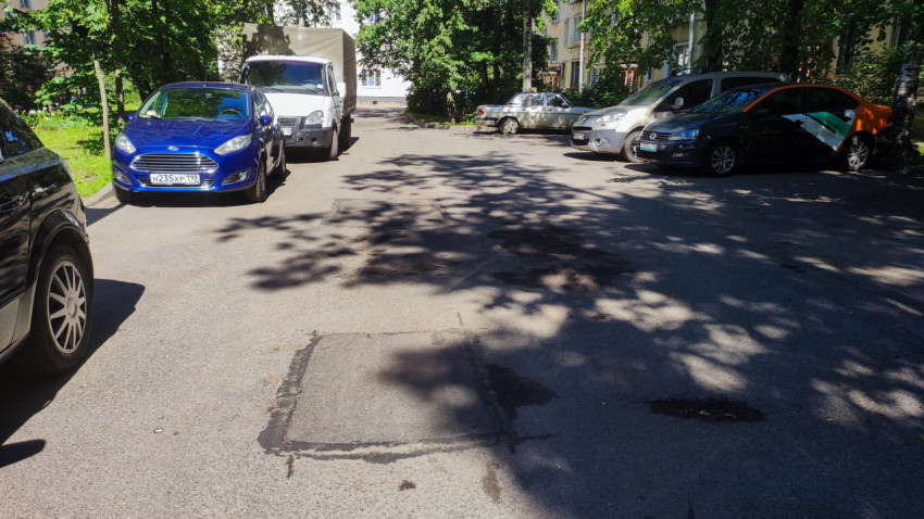 Дворовая парковка с автомобилями и участками ремонта асфальта