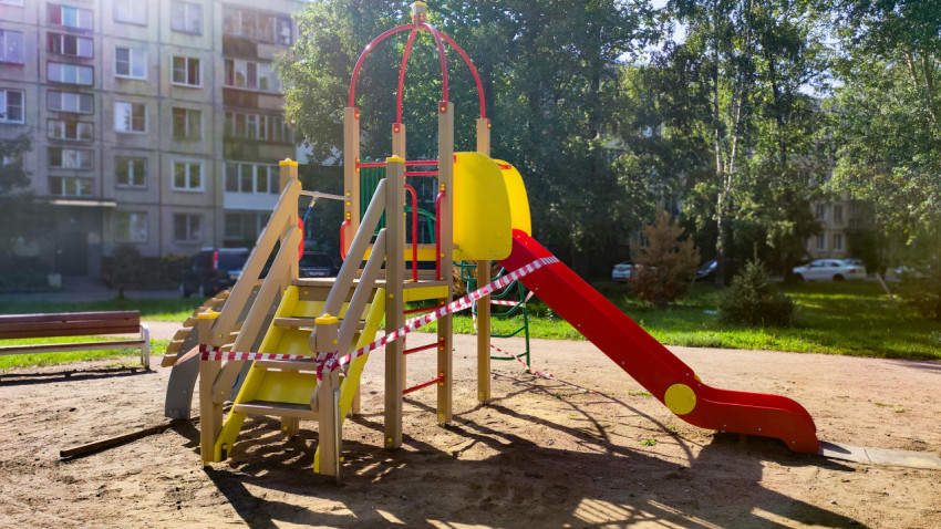 Новая детская площадка с игровой горкой, ограждённая лентой