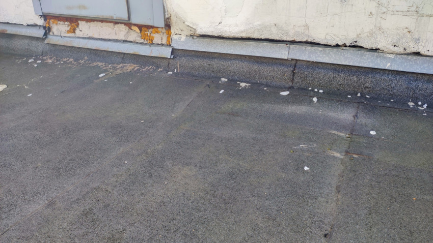 Кровельное покрытие у стены здания с дефектами