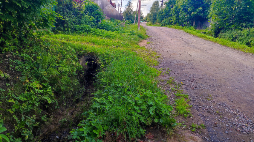 Грунтовая дорога и водоотводная труба в канаве
