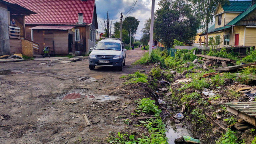 Деревенская улица с автомобилем и канавой