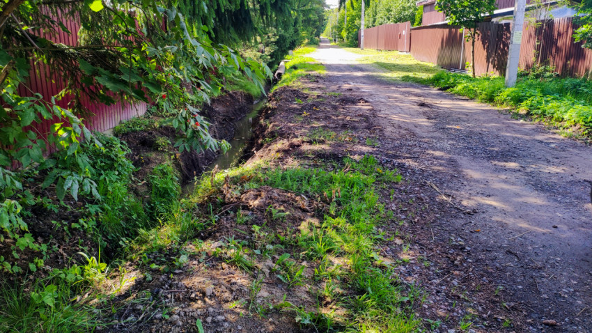 Канава вдоль грунтовой дороги у частных домов