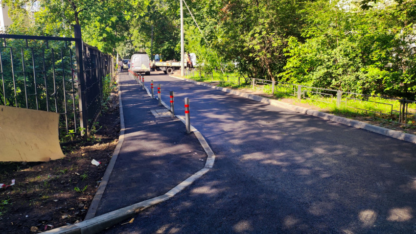 Дворовая дорога с ограждением и припаркованными машинами