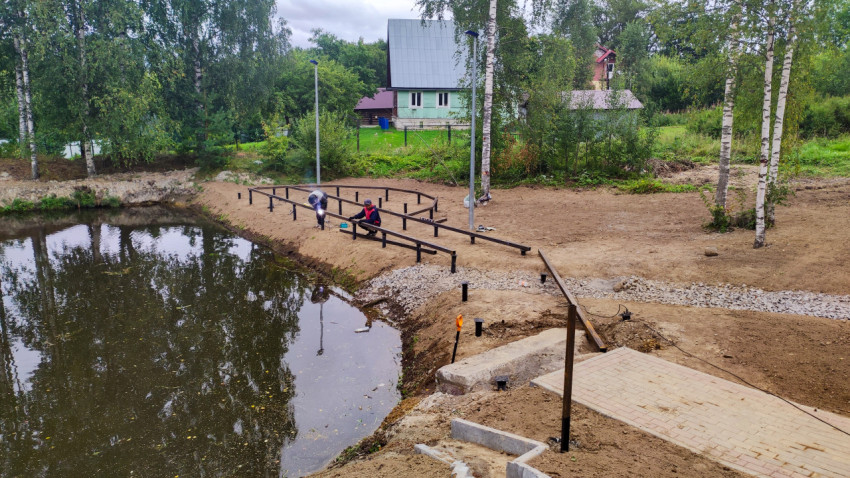 Рабочие устанавливают ограждение на берегу пруда
