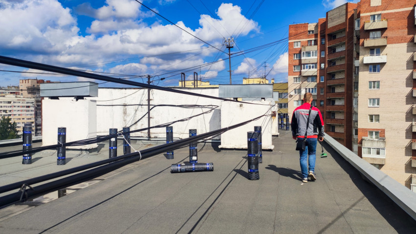 Рабочий на крыше жилого дома с материалами для ремонта