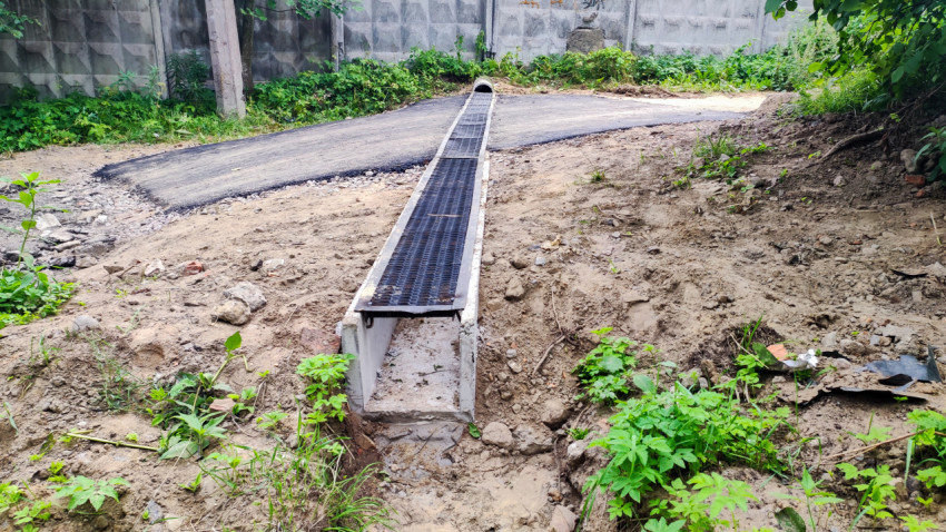 Дренажный канал с металлической решеткой на грунтовом участке