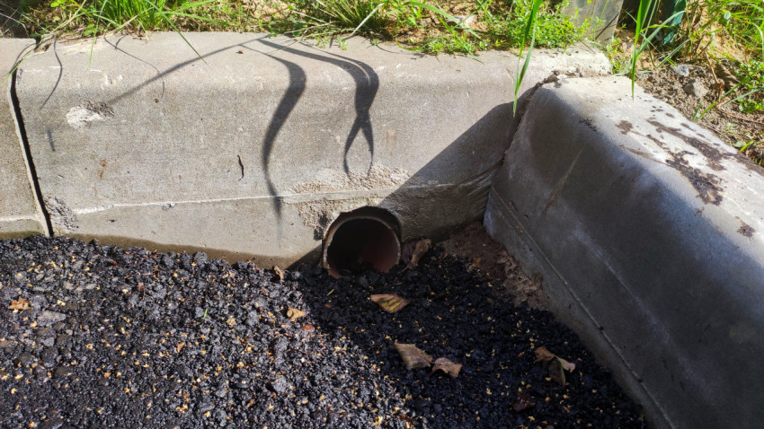 Ливнёвый отвод воды в бордюре асфальтовой дороги